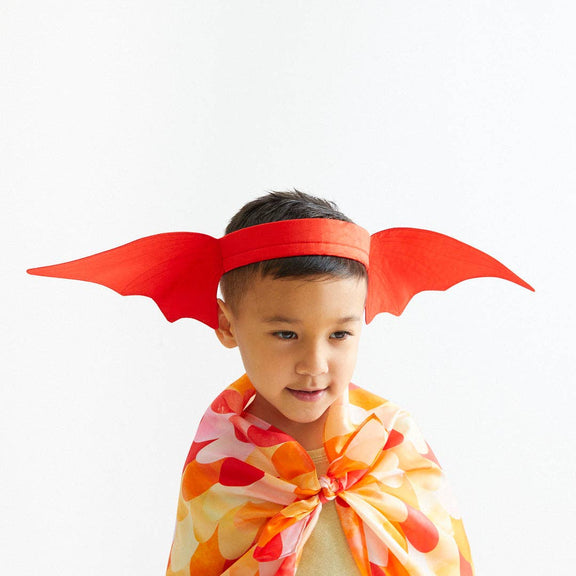 Child wearing red devil horns and a colorful cape on a white background