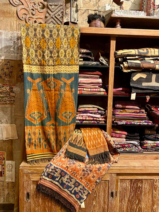 Display of patterned fabrics in a store setting with wooden shelves.