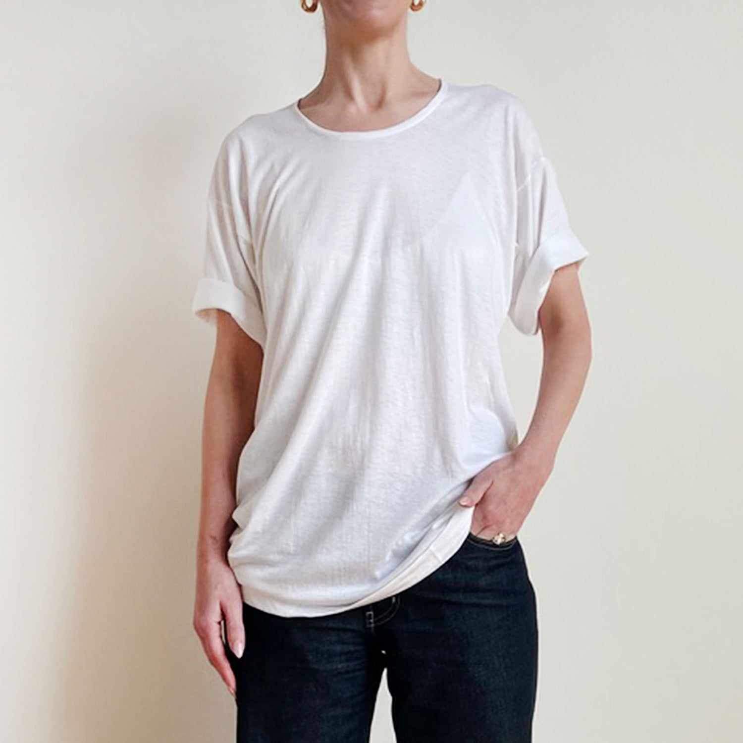 Person wearing a plain white t-shirt and dark jeans against a light background