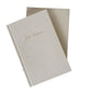 Two beige notebooks with embossed text on a white background