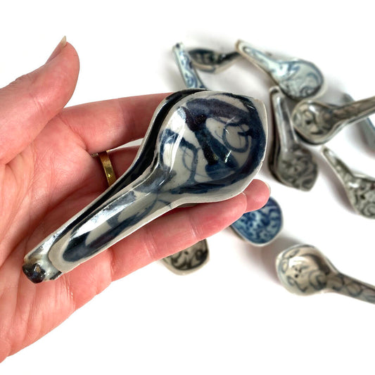 Hand holding small ceramic spoon with dark blue brushstroke glaze pattern
